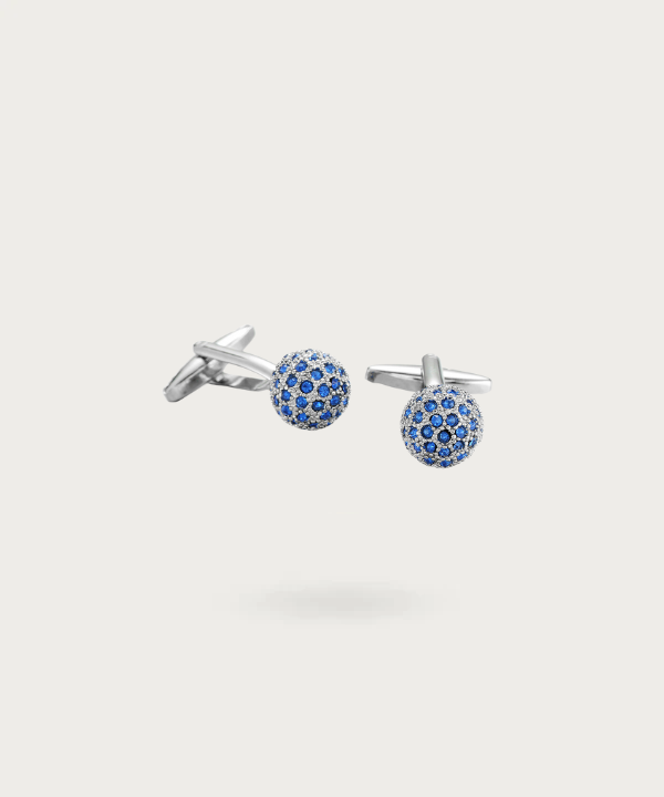 Boutons de manchette en forme de boule argenté avec brillants bleus, symbolisant l'essence de la noblesse.