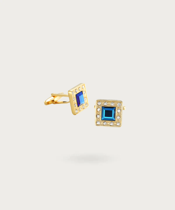 Boutons de manchette en forme de carré doré avec brillants bleus enchâssés, symbolisant l'élégance et le luxe."
